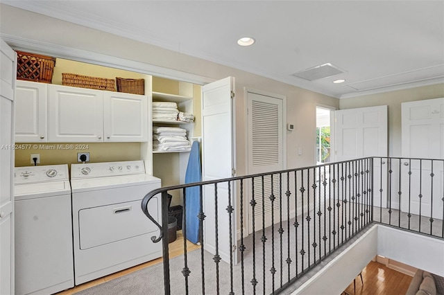 laundry area with washing machine and clothes dryer, attic access, light wood finished floors, cabinet space, and ornamental molding