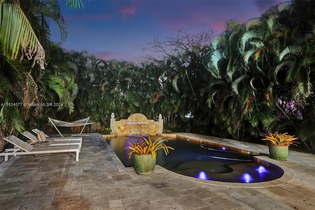 pool at dusk featuring a patio