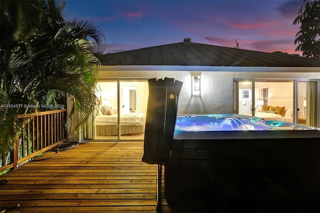 rear view of house with a standing seam roof, metal roof, a hot tub, a deck, and stucco siding