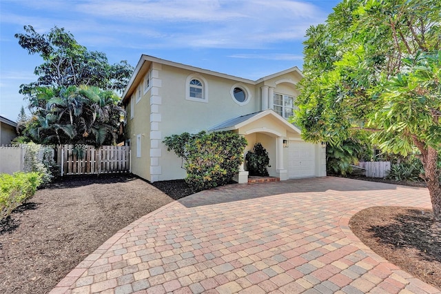 view of front of house featuring fence, decorative driveway, and stucco siding