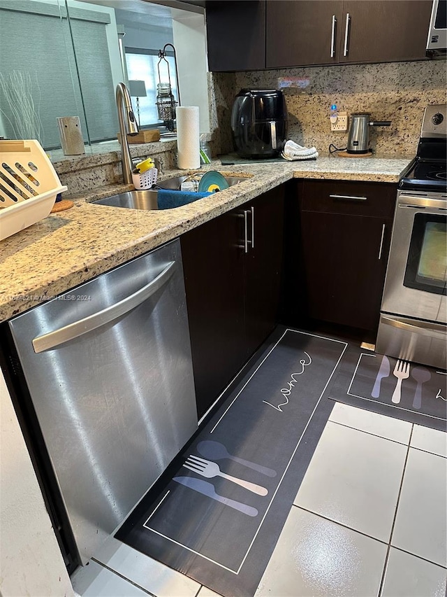 kitchen featuring tasteful backsplash, stainless steel appliances, dark tile patterned floors, sink, and dark brown cabinetry