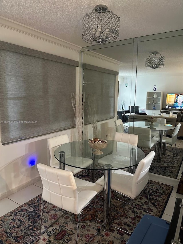 tiled dining space featuring a notable chandelier, ornamental molding, and a textured ceiling