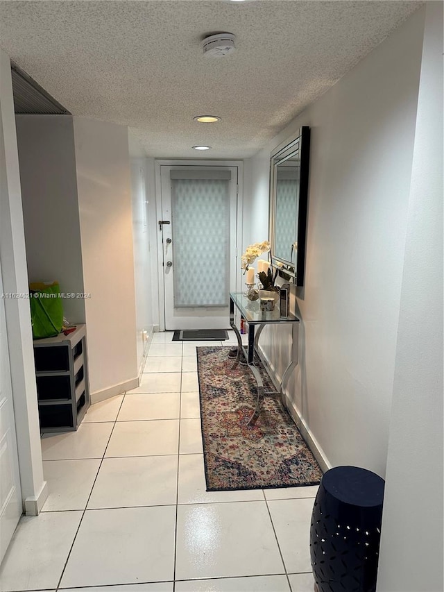 hall featuring light tile patterned flooring and a textured ceiling