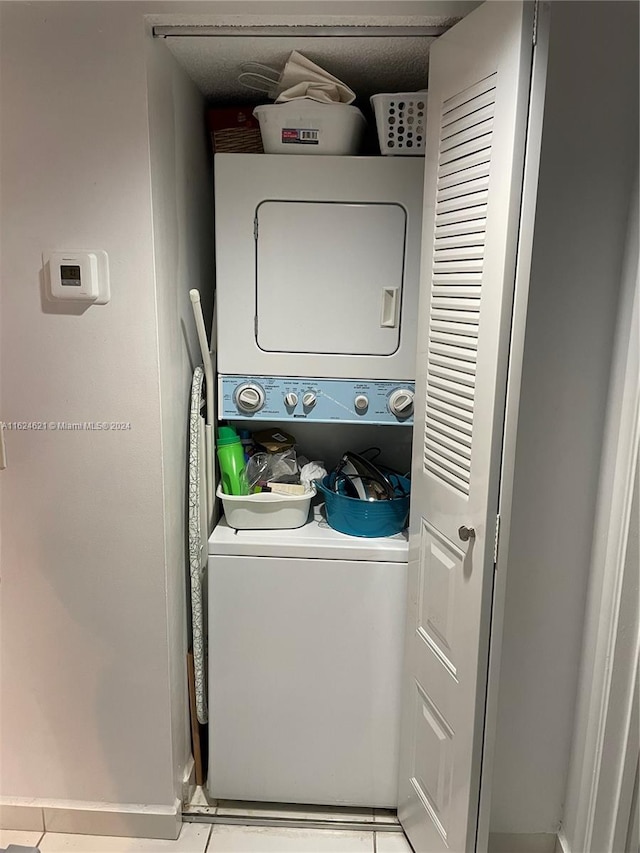 laundry room with stacked washer and dryer and light tile patterned floors