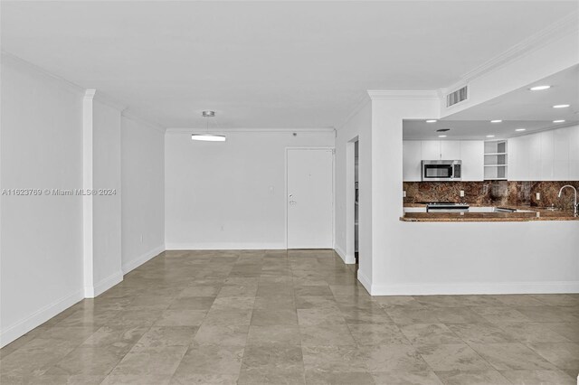 unfurnished living room with sink, ornamental molding, and light tile patterned floors