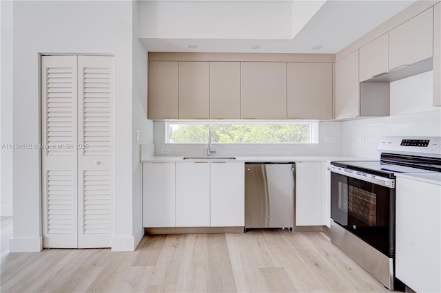 kitchen with appliances with stainless steel finishes, sink, light wood-type flooring, and plenty of natural light