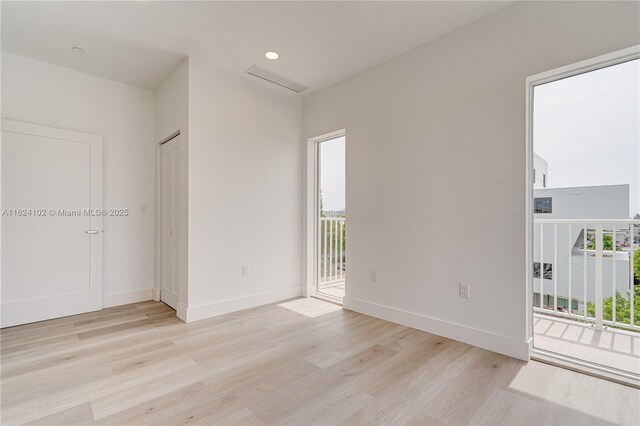 empty room featuring baseboards, plenty of natural light, and light wood finished floors