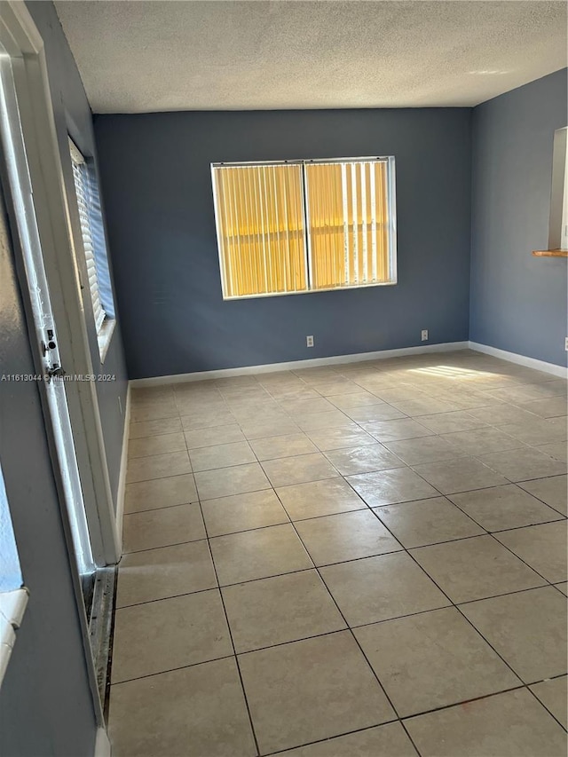 tiled spare room featuring a textured ceiling