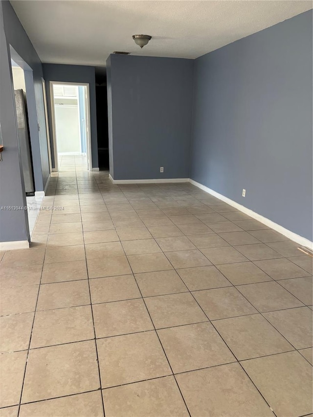 spare room featuring light tile patterned floors and a textured ceiling