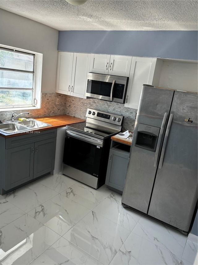 kitchen with white cabinetry, sink, stainless steel appliances, gray cabinets, and decorative backsplash