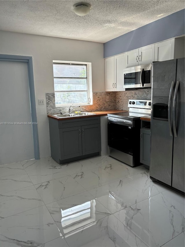 kitchen featuring white cabinets, appliances with stainless steel finishes, gray cabinets, and sink