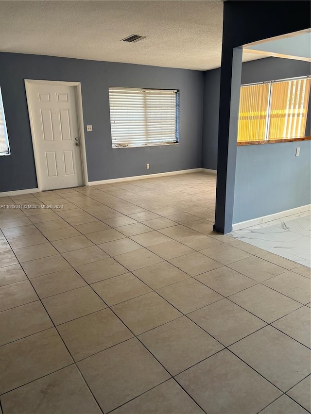 tiled empty room with a textured ceiling