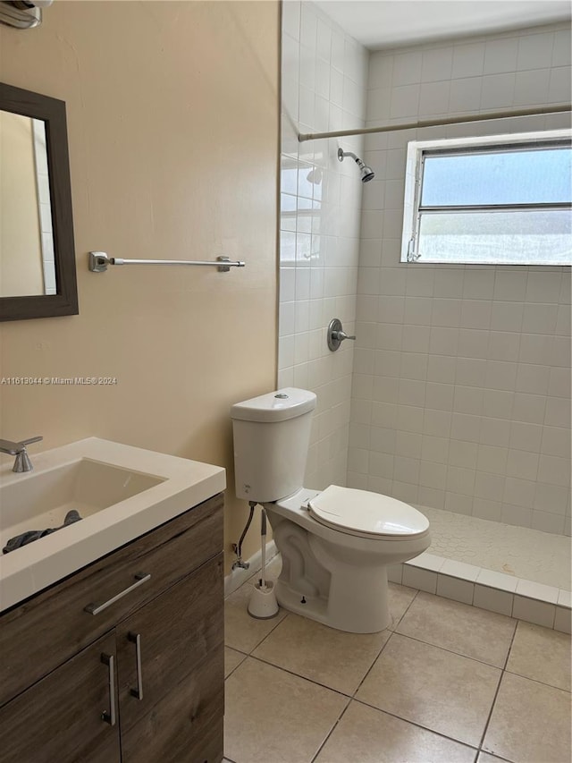 bathroom with tiled shower, tile patterned flooring, vanity, and toilet