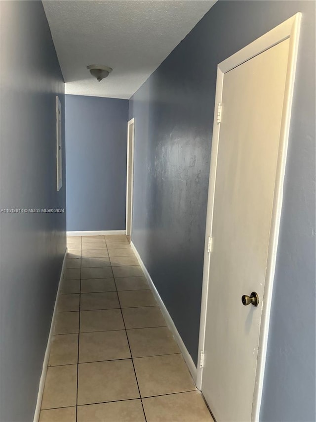 hallway featuring light tile patterned floors and a textured ceiling