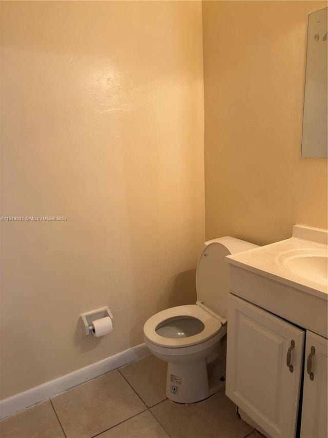 bathroom with toilet, vanity, and tile patterned floors