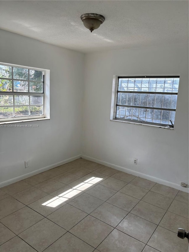 tiled empty room featuring a textured ceiling