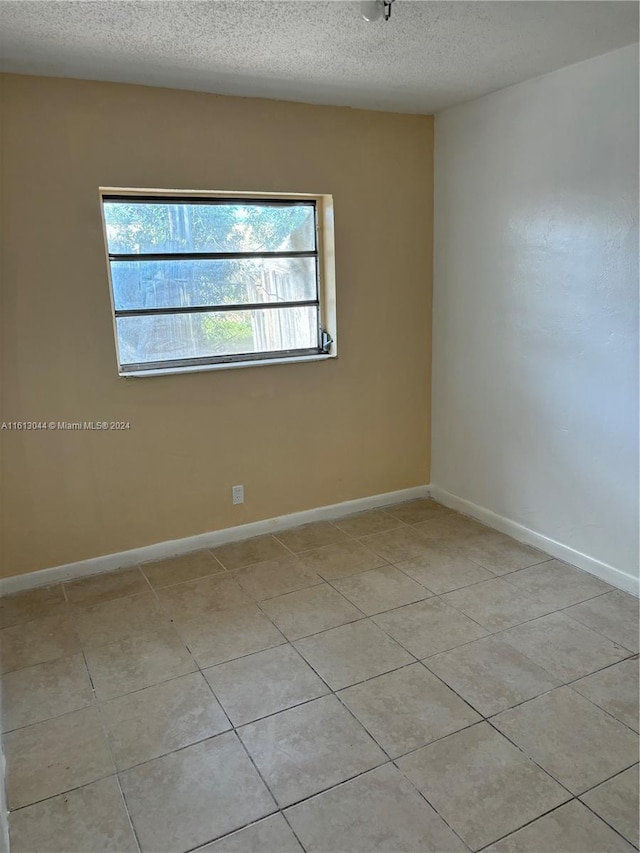 spare room featuring light tile patterned floors and a textured ceiling