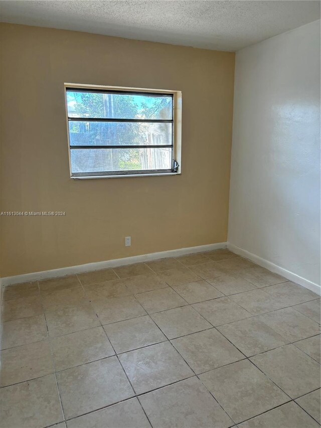 tiled empty room with a textured ceiling