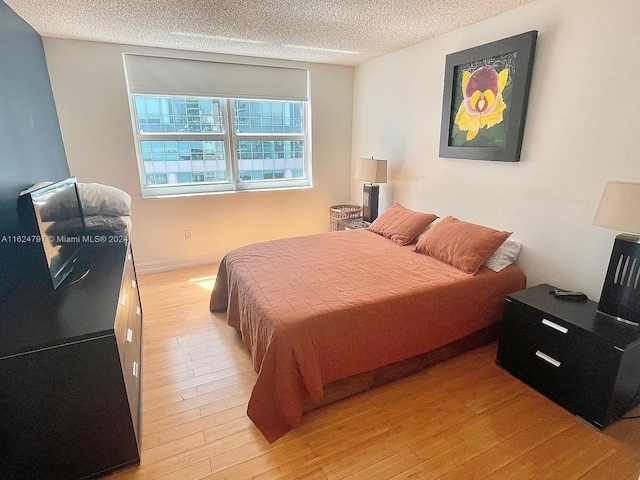 bedroom featuring light hardwood / wood-style floors and a textured ceiling