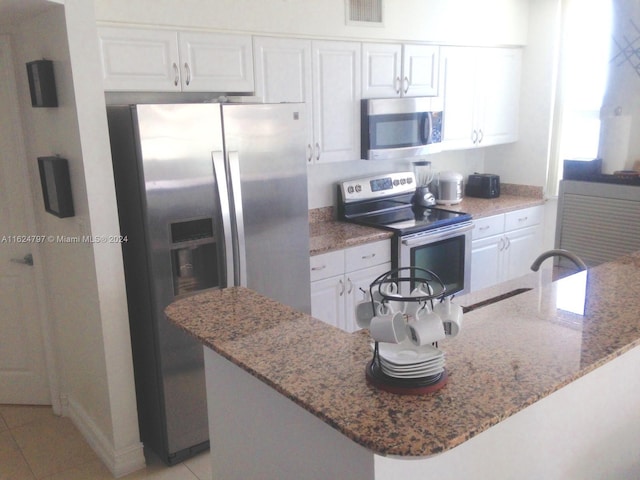 kitchen featuring light tile patterned floors, stainless steel appliances, white cabinets, and light stone counters