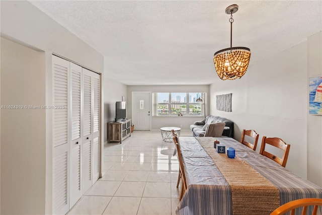 tiled dining space featuring a notable chandelier and a textured ceiling