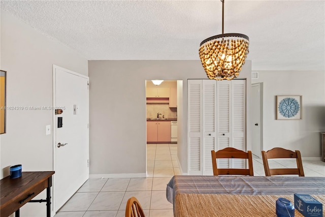 dining space featuring sink, light tile patterned floors, a chandelier, and a textured ceiling