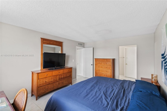 bedroom with a closet, light tile patterned floors, and a textured ceiling