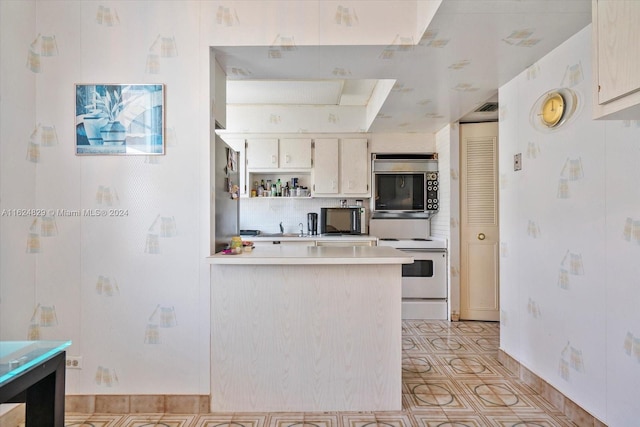 kitchen with white electric range oven, backsplash, and kitchen peninsula