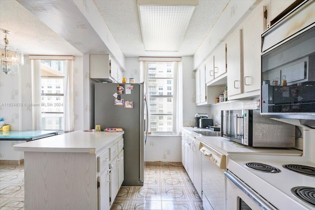 kitchen with white cabinets, appliances with stainless steel finishes, and a healthy amount of sunlight