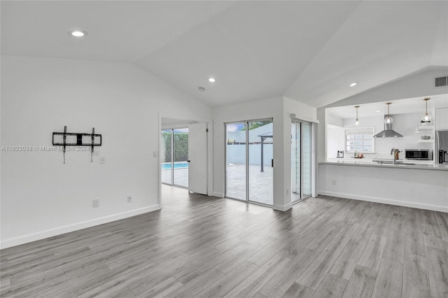 unfurnished living room featuring sink, vaulted ceiling, and light hardwood / wood-style floors