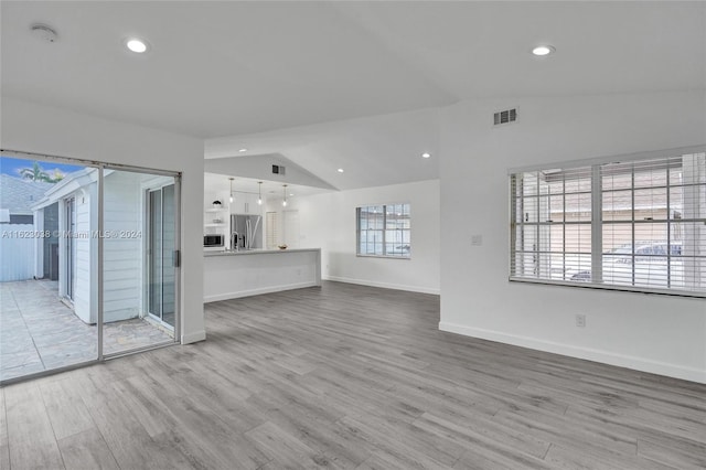 unfurnished living room with wood-type flooring and vaulted ceiling