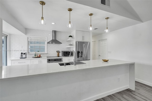 kitchen with light hardwood / wood-style flooring, white cabinetry, stainless steel appliances, decorative backsplash, and wall chimney exhaust hood