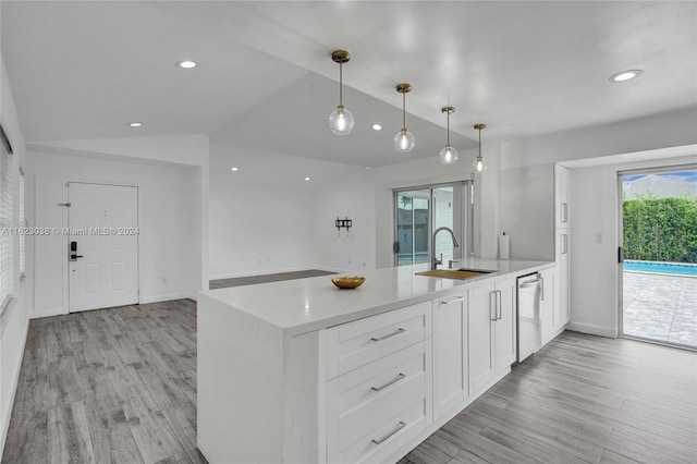 kitchen with sink, vaulted ceiling, hanging light fixtures, stainless steel dishwasher, and white cabinets