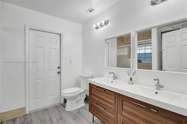 bathroom with a shower with door, vanity, hardwood / wood-style floors, and toilet