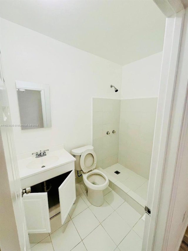 bathroom featuring tile patterned floors, vanity, toilet, and a tile shower