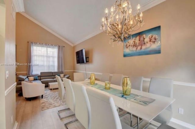 dining space with a notable chandelier, vaulted ceiling, crown molding, and light hardwood / wood-style flooring