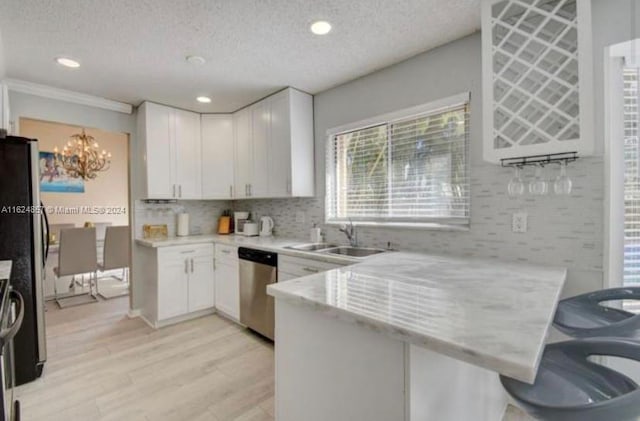 kitchen featuring light hardwood / wood-style flooring, white cabinets, tasteful backsplash, sink, and stainless steel dishwasher