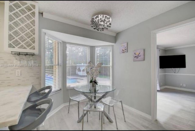 dining area with a textured ceiling, an inviting chandelier, light wood-type flooring, and plenty of natural light