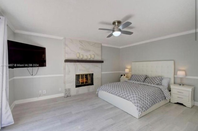 bedroom with a fireplace, light hardwood / wood-style flooring, ornamental molding, and ceiling fan