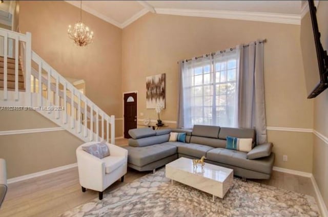 living room with hardwood / wood-style flooring, vaulted ceiling, ornamental molding, and an inviting chandelier