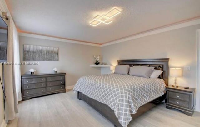 bedroom with ornamental molding and light wood-type flooring