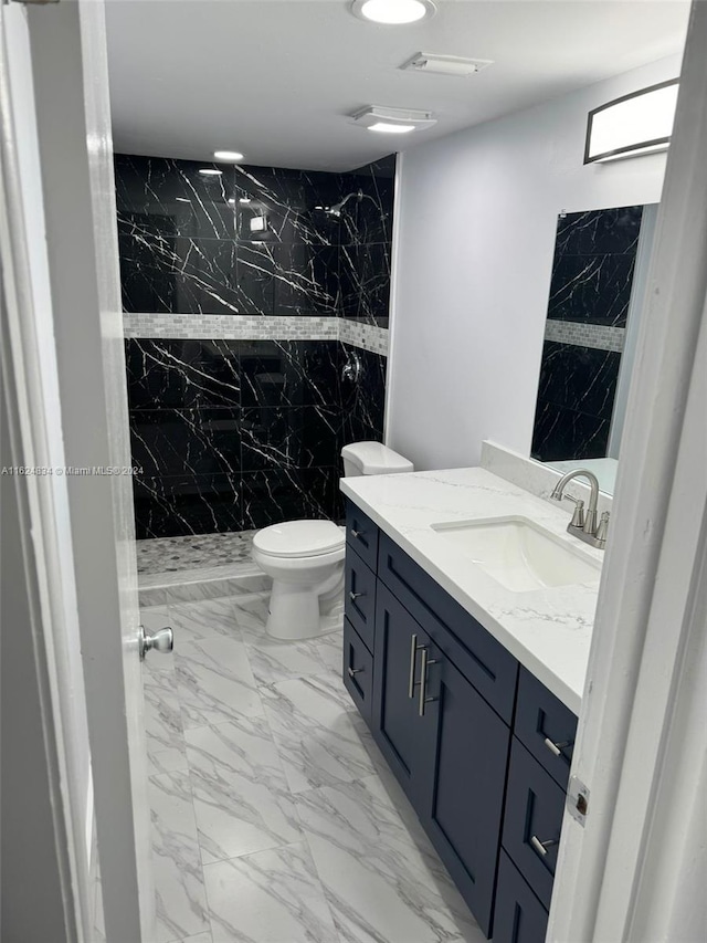 bathroom featuring vanity, toilet, and a tile shower