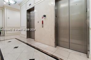 hallway with elevator and light tile patterned floors