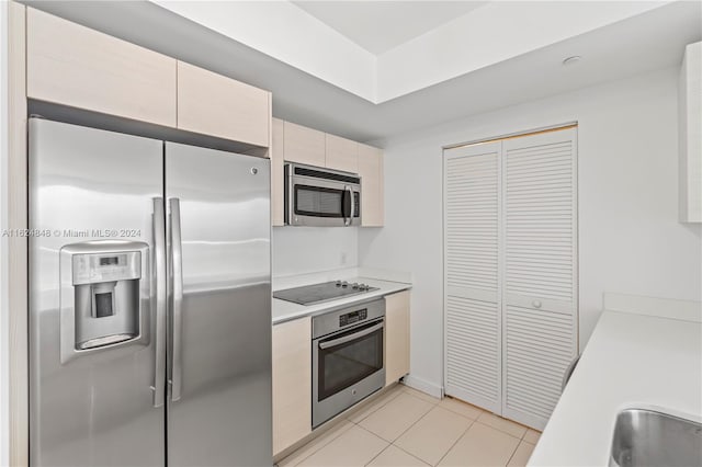 kitchen featuring cream cabinets, light tile patterned floors, and stainless steel appliances