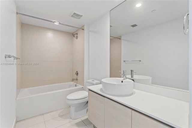 full bathroom with tile patterned flooring, toilet, tiled shower / bath combo, and vanity