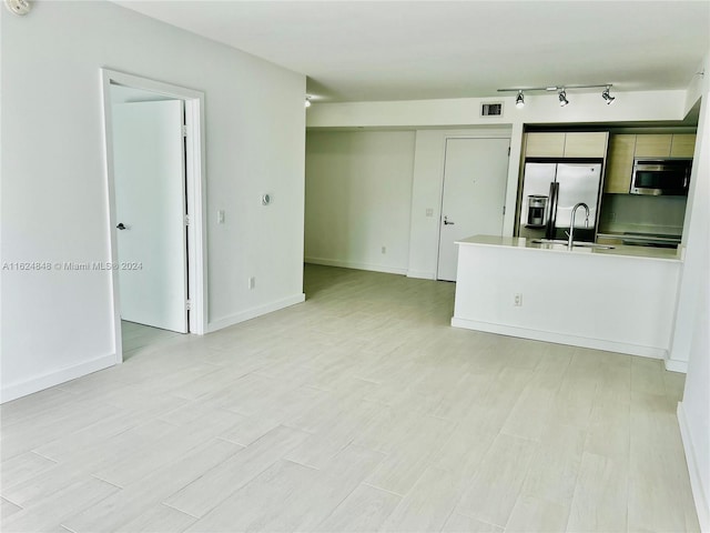 unfurnished living room featuring light wood-type flooring, rail lighting, and sink