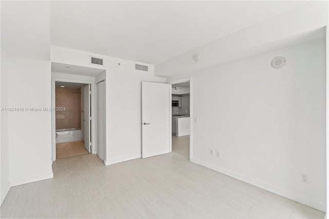 unfurnished bedroom with light tile patterned flooring and connected bathroom