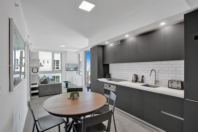 kitchen with sink, backsplash, black electric stovetop, and stainless steel oven