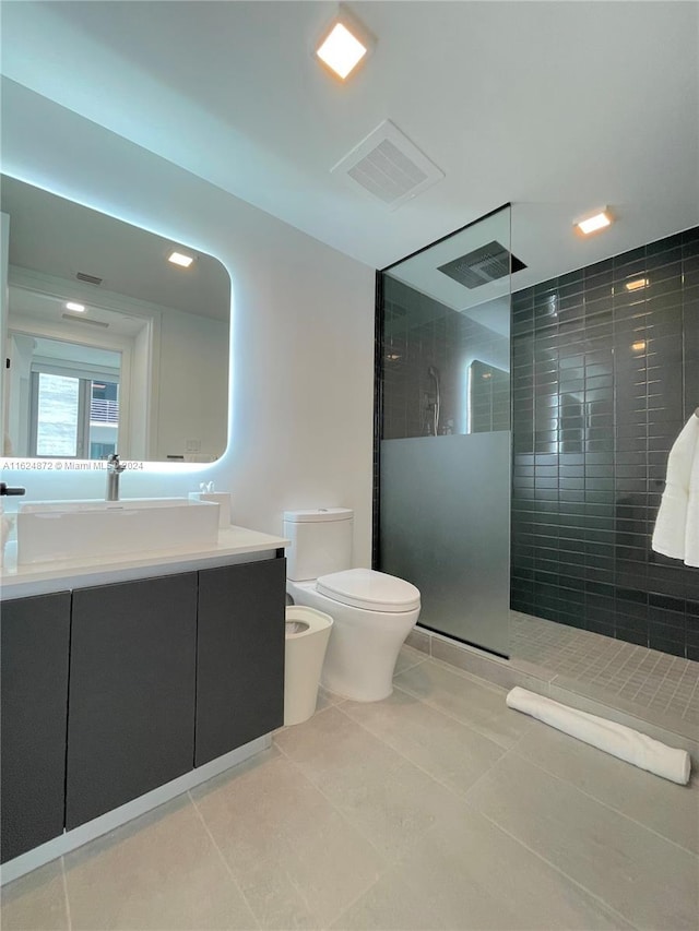 bathroom featuring tile patterned floors, toilet, vanity, and a tile shower