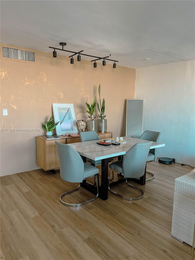 dining area with light hardwood / wood-style flooring and rail lighting